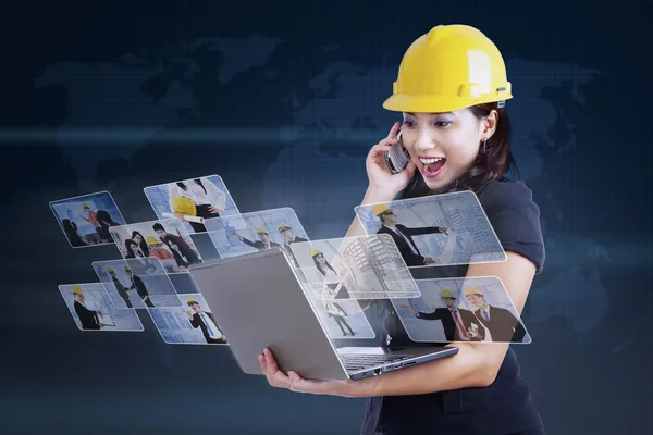 Excited contractor looking at laptop on blue — Stock Photo, Image