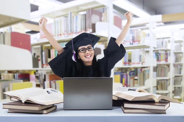 Happy graduate at library with laptop — Stock Photo, Image