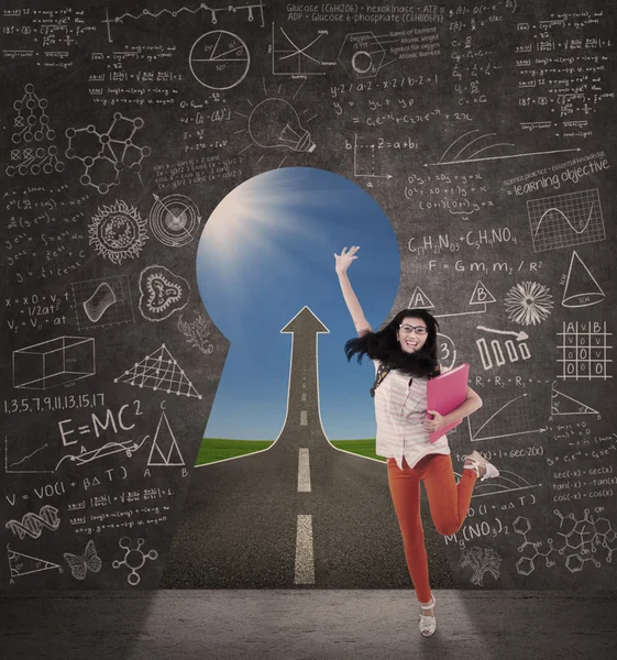 Excited female student jump in class with up arrow sign — Stock Photo, Image