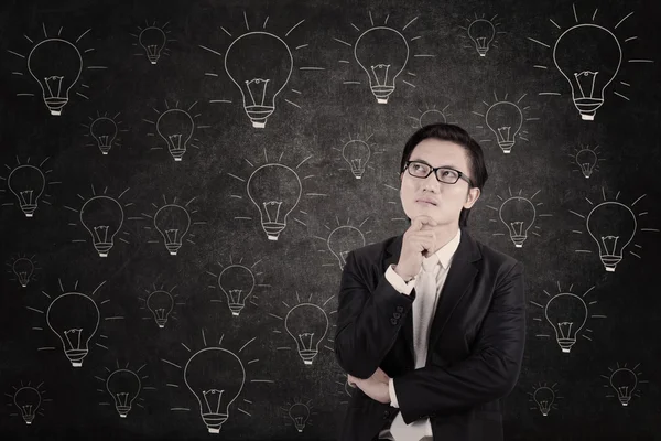 Asian businessman concentrating on lightbulbs blackboard — Stock Photo, Image