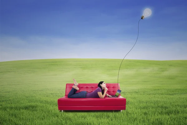 Attraktive Frau liegt auf rotem Sofa unter Lampe im Freien — Stockfoto