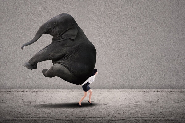 Businesswoman lifting heavy elephant