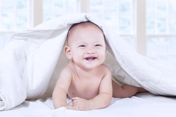 Bebê rindo sob cobertor em casa — Fotografia de Stock