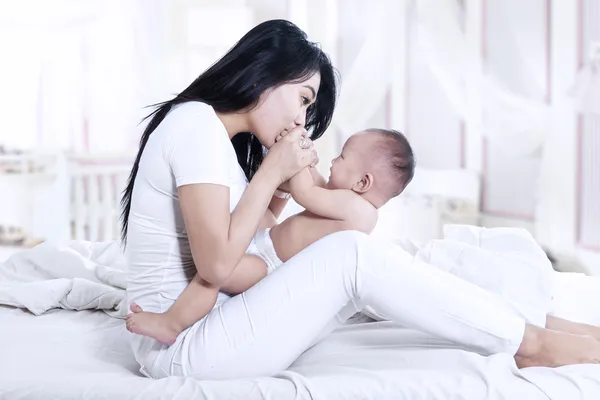 Hermosa madre besando bebé en casa — Foto de Stock