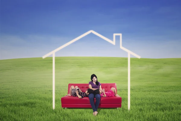 Madre e figli su campo verde con casa da sogno Foto Stock