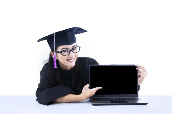 Absolventin zeigt auf leeren Laptop-Bildschirm — Stockfoto