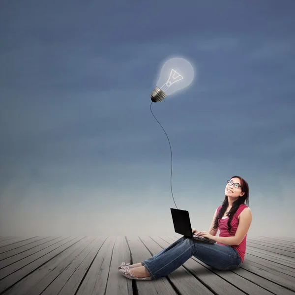 Beautiful female using laptop under lit bulb outdoor — Stock Photo, Image