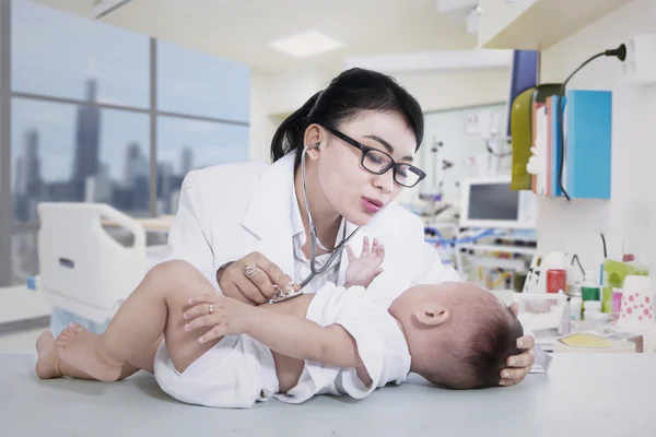 Belo médico verificando bebê na clínica — Fotografia de Stock