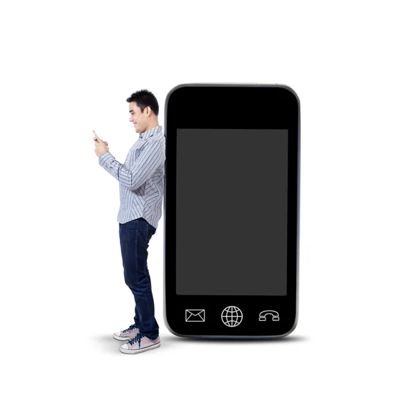 Азиатский мужчина с помощью мобильного телефона и стоя рядом с большим смартфоном — стоковое фото