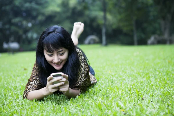 Sorridente ragazza asiatica utilizzando un telefono — Foto Stock