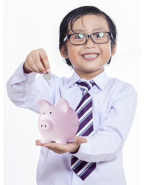 Rapaz coloca a moeda num banco porquinho — Fotografia de Stock