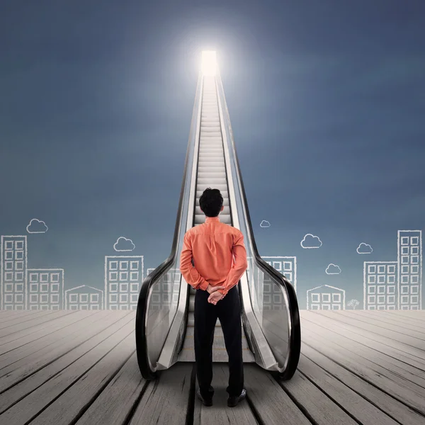 Businessman at escalator under bright sky — Stock Photo, Image