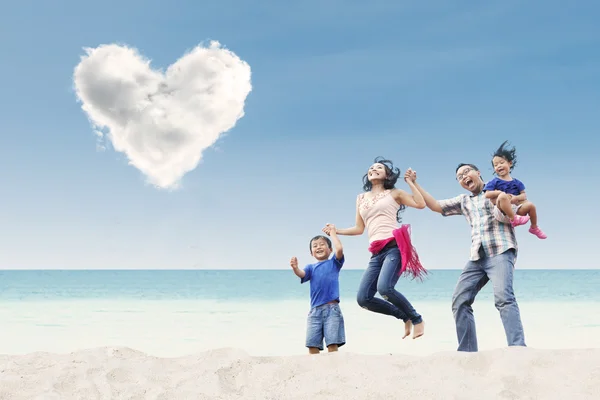 Азиатская семья прыгает под облаком сердца — стоковое фото
