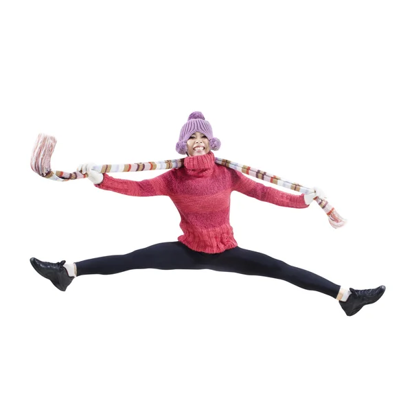 Молодая женщина прыгает и улыбается в зимней одежде — стоковое фото