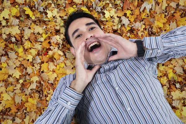 Asian young man shouting on leaves — Stock Photo, Image