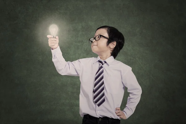 Confident business kid holding lit bulb — Stock Photo, Image