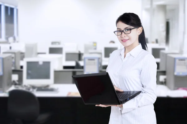 Trabalhadora feminina atraente segurando laptop no escritório — Fotografia de Stock