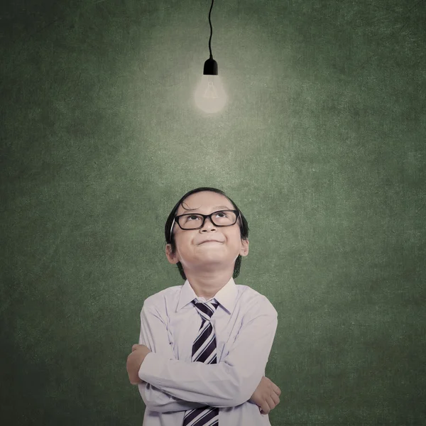 Young businessman under lit bulb in class — Stock Photo, Image