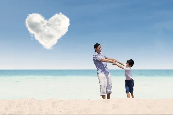 Père et fils à la plage sous nuage d'amour — Photo