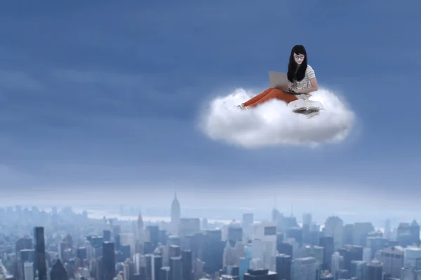 Female student sitting with laptop on a cloud — Stock Photo, Image