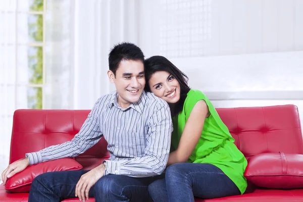 Casal jovem relaxante em um sofá vermelho em casa — Fotografia de Stock