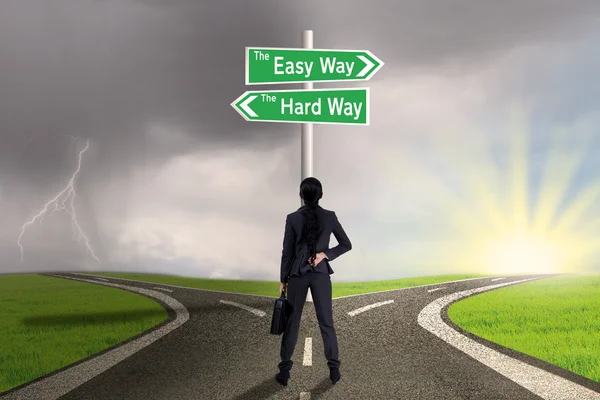 Businesswoman looking at sign of easy vs hard way — Stock Photo, Image