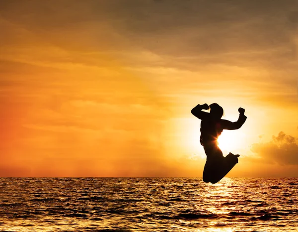 Silhueta de mulher pulando ao pôr do sol — Fotografia de Stock