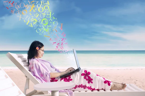 Mujer usando un portátil en la playa — Foto de Stock