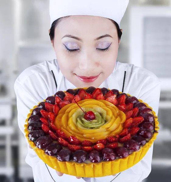 Chef feminino segurando um bolo delicioso — Fotografia de Stock