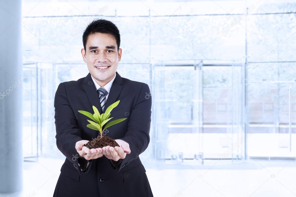 Smiling businessman holding a plant