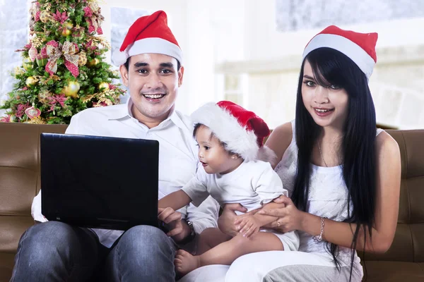 Lycklig familj i santa hattar med laptop — Stockfoto