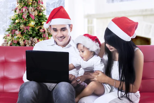 Famille heureuse dans le chapeau de Père Noël en utilisant un ordinateur portable — Photo