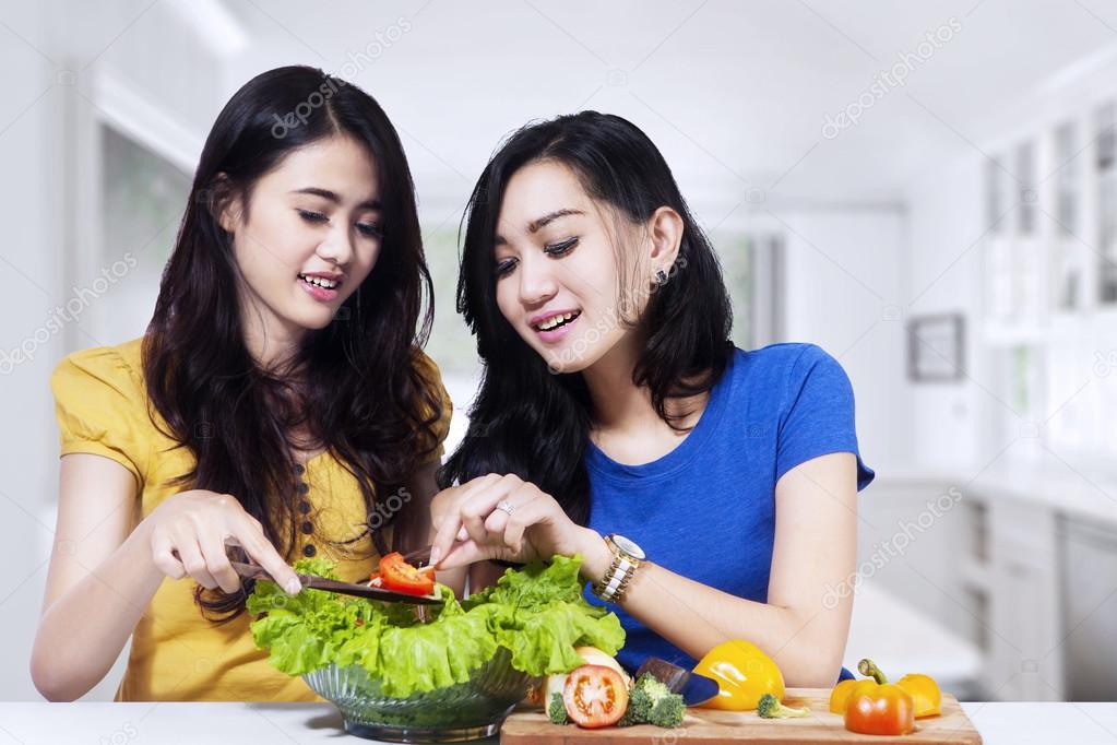 Two women cooking vegetables salad
