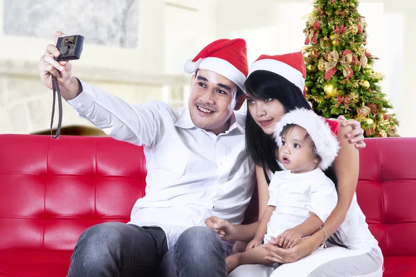 Familia en sombreros de Santa Claus tomando fotos —  Fotos de Stock