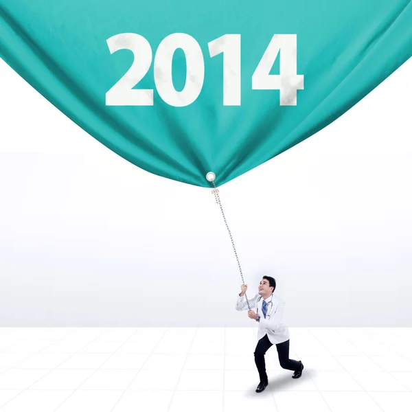 Male doctor pulls a banner of new year 2014 — Stock Photo, Image