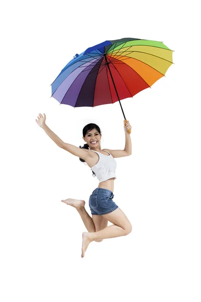 Woman jumping with rainbow umbrella — Stock Photo, Image