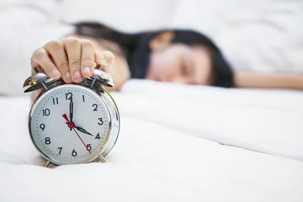 Wekker met slapende vrouw op bed — Stockfoto