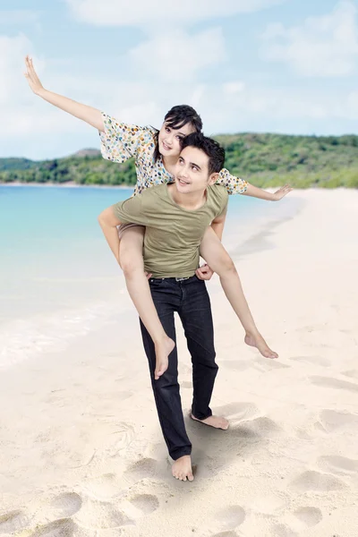 Pojkvän ger piggyback rida på stranden — Stockfoto