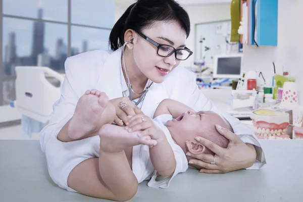 Hermoso médico comprobar llorando bebé en la clínica — Foto de Stock
