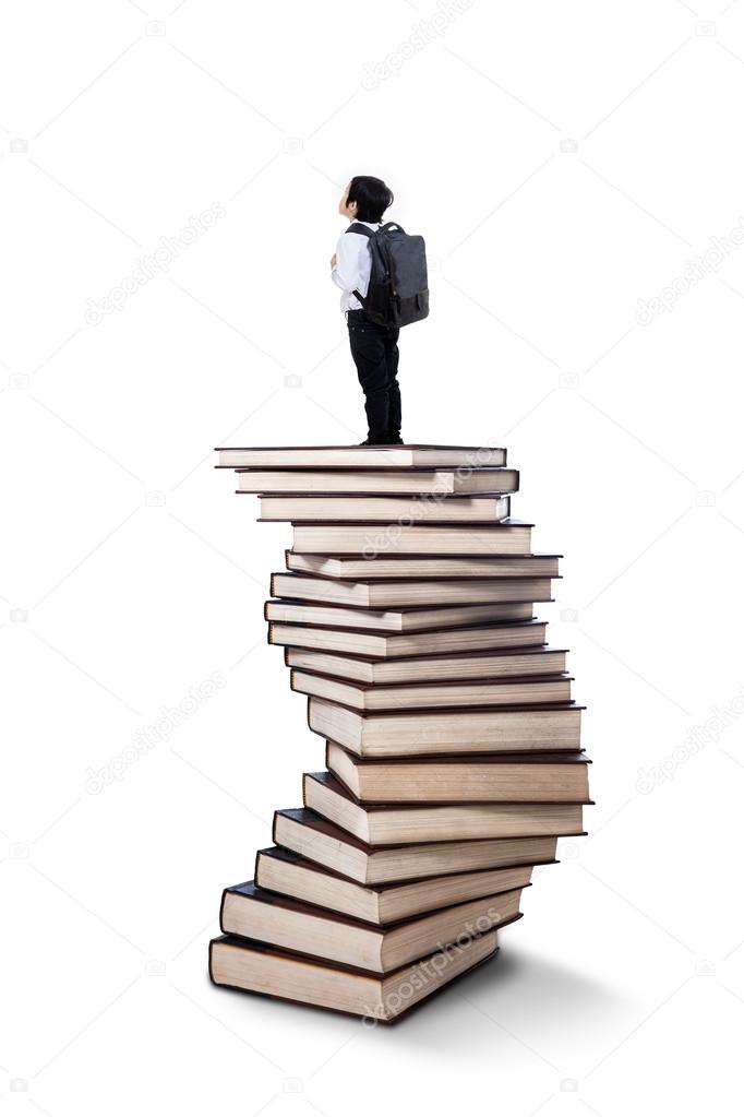 Little boy standing on books stack