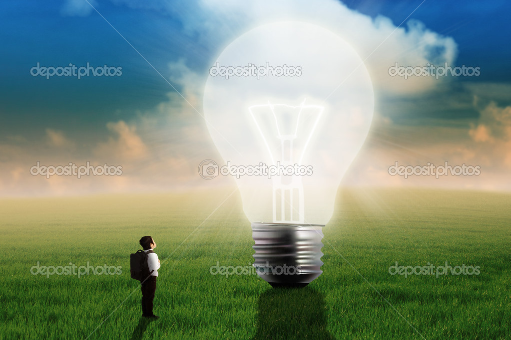 Little boy looking at big light bulb