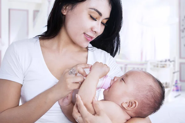 Mãe atraente alimentando seu bebê em casa — Fotografia de Stock