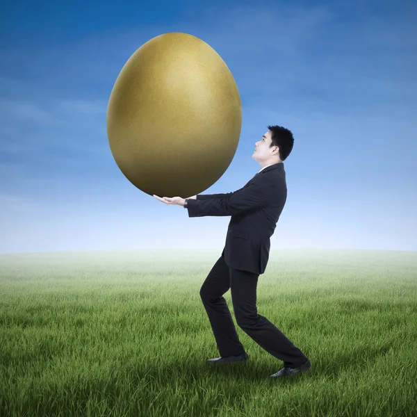 Zakenman houden een gouden ei — Stockfoto