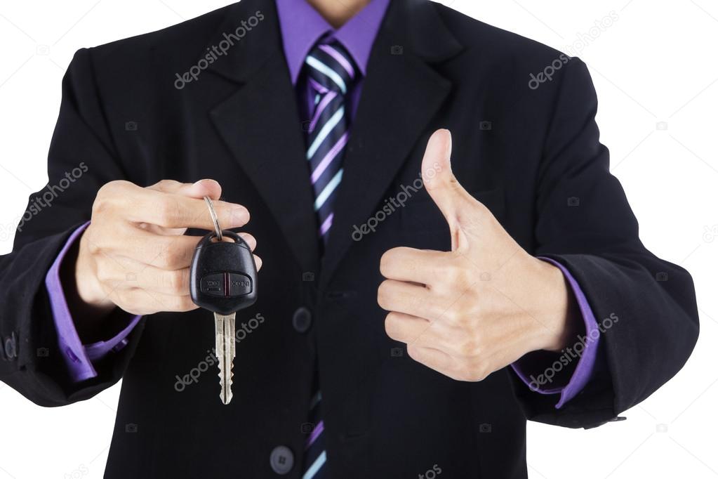 Businessman offering a car key with thumbs-up