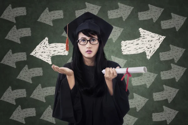 Förvirrad kvinnlig student i gradering klänning — Stockfoto