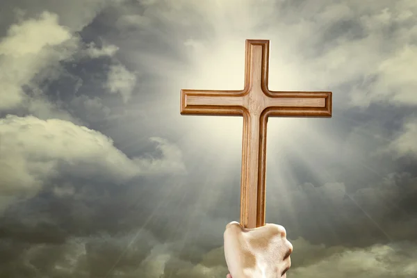 Рука с крестом над небом — стоковое фото