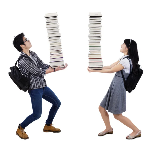 Casal jovem carregando uma pilha de livros — Fotografia de Stock