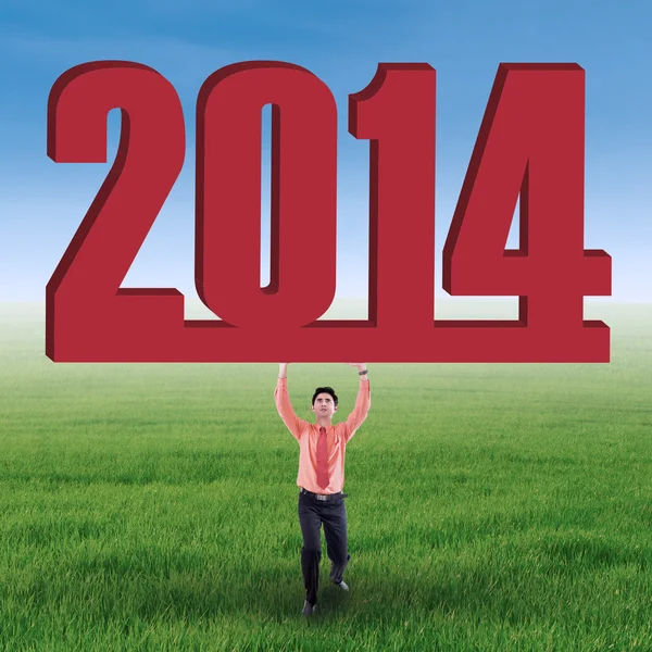 Businessman lifting new year 2014 on the field — Stock Photo, Image