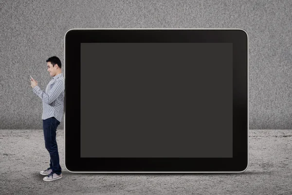 A man writes an SMS and standing by a big tablet — Stock Photo, Image