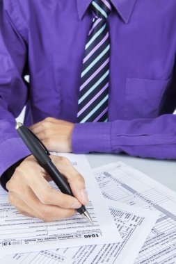 Businessman hand filling out a tax form clipart